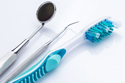 An image featuring dental instruments, including a toothbrush with blue bristles and an assortment of other dental tools, displayed on a white background.