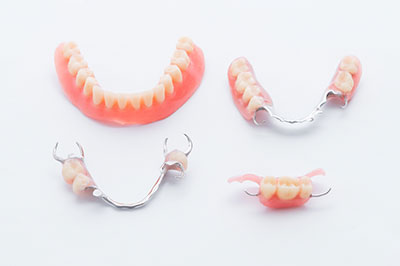 The image shows three sets of dentures with teeth missing, displayed on a white surface against a plain background.