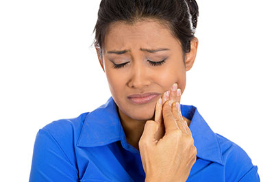 The image shows a woman with her eyes closed, holding her face with both hands, seemingly distressed, with a blue background.