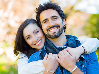 Two people, likely a couple, embracing each other with smiles on their faces.