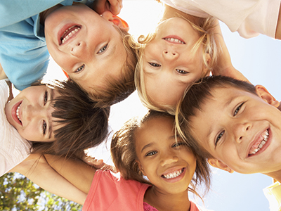 The image depicts a group of children happily posing together with smiles on their faces.