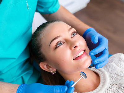 A dental hygienist is performing a teeth cleaning procedure on a patient s mouth.