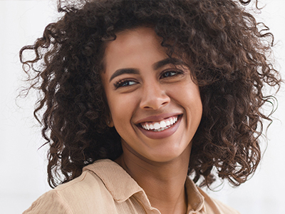 A woman with curly hair smiles at the camera.